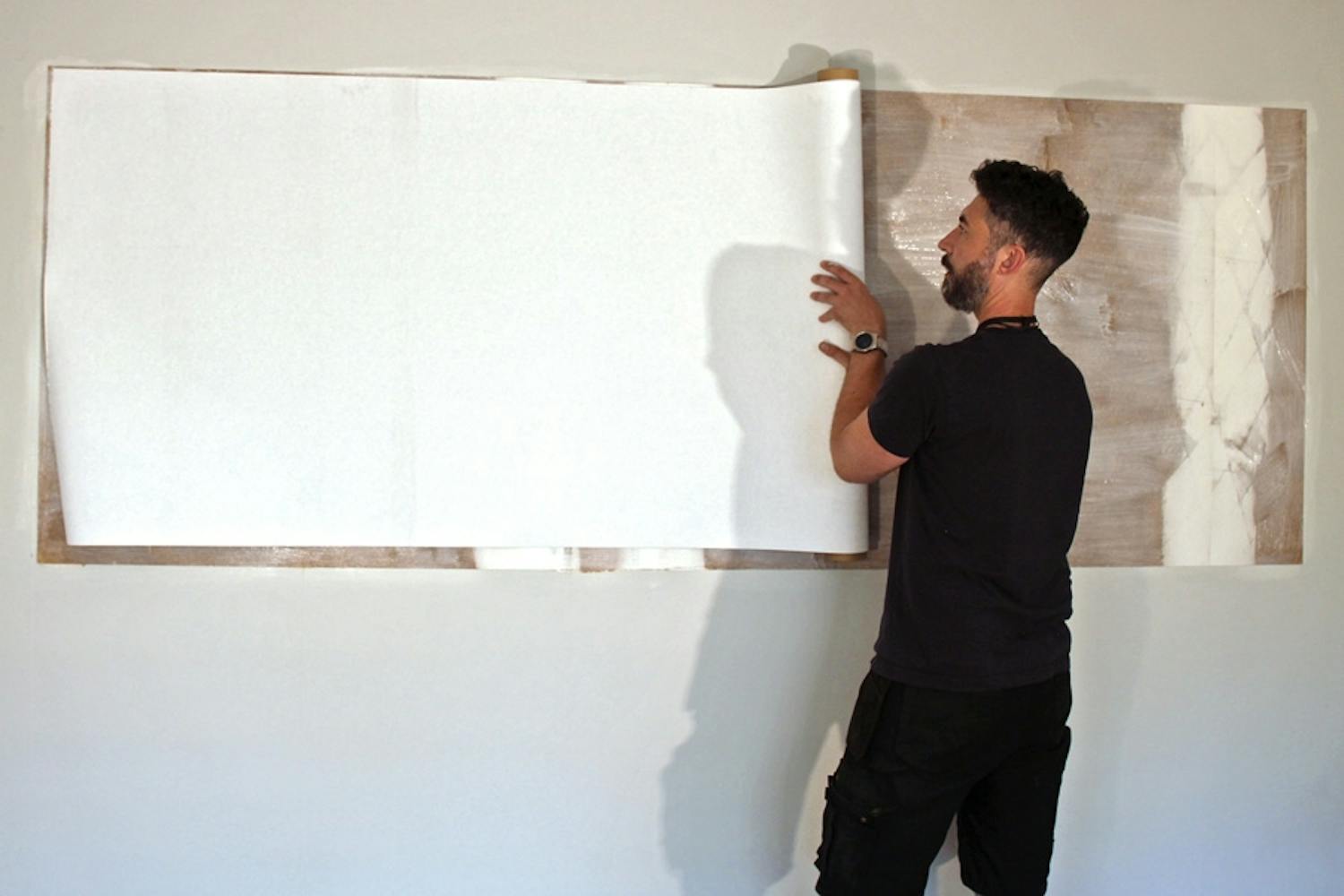 Det magnetiske tapetet rulles på veggen, som er smurt inn med godt med tapetlim. Det magnetiske tapetet rulles på veggen, som er smurt inn med godt med tapetlim.